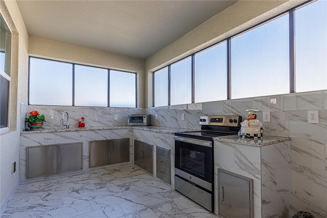 kitchen featuring backsplash, light stone countertops, and stainless steel range with electric stovetop