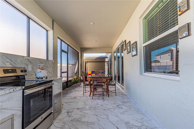 exterior space with light tile floors, backsplash, light stone counters, and electric range