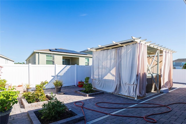 exterior space with a patio area, a pergola, and solar panels