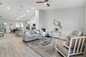 living room with lofted ceiling, light hardwood / wood-style floors, and ceiling fan