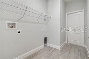 laundry room with electric dryer hookup and light hardwood / wood-style floors