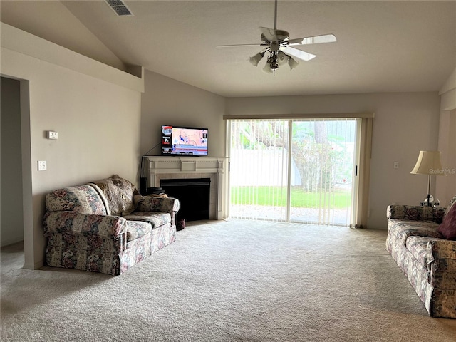 carpeted living room with ceiling fan, lofted ceiling, and a tile fireplace