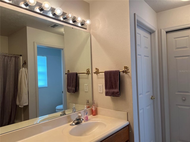 bathroom with vanity with extensive cabinet space and toilet