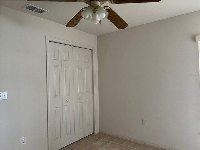 unfurnished bedroom featuring a closet, light carpet, and ceiling fan