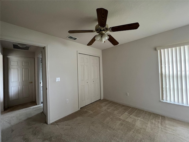 unfurnished bedroom with dark colored carpet, multiple windows, a closet, and ceiling fan