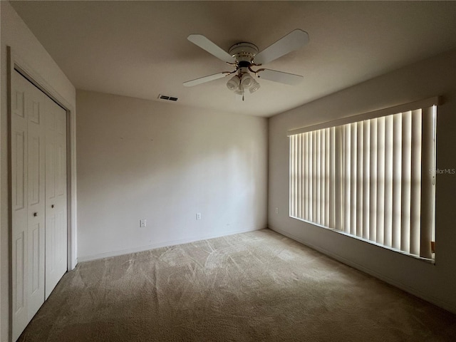 unfurnished bedroom featuring a closet, light carpet, and ceiling fan