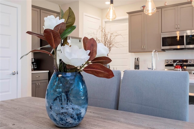 kitchen with stove, gray cabinetry, pendant lighting, and light wood-type flooring