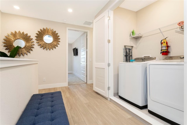 laundry room with light wood-type flooring and washer and clothes dryer