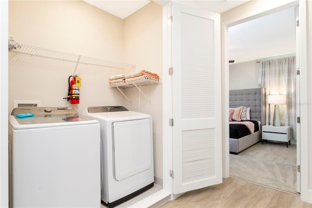 clothes washing area with washer and clothes dryer and light colored carpet