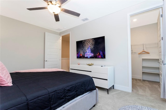 bedroom with light carpet, a walk in closet, and ceiling fan