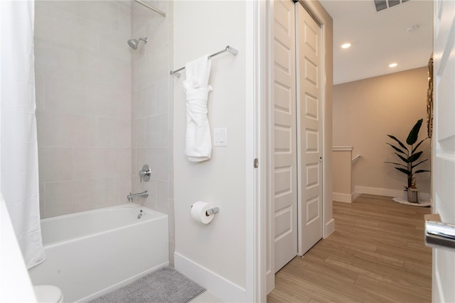 bathroom featuring toilet, shower / tub combo with curtain, and hardwood / wood-style flooring