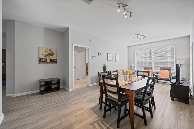 dining space with light hardwood / wood-style flooring and track lighting