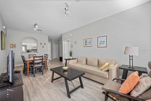 living room featuring rail lighting and light hardwood / wood-style flooring