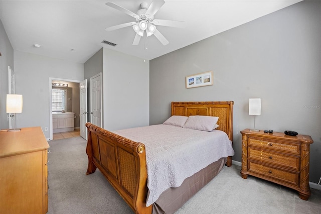 bedroom with a closet, ensuite bath, ceiling fan, and light colored carpet