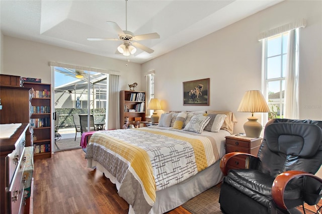 bedroom featuring a raised ceiling, access to exterior, ceiling fan, and dark wood-type flooring