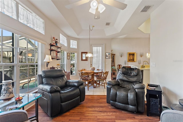 living room with hardwood / wood-style floors, a tray ceiling, ceiling fan, and a wealth of natural light