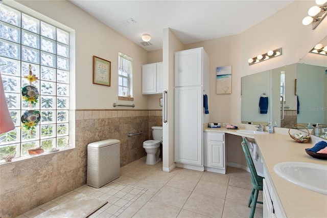 bathroom featuring tile walls, toilet, double sink, vanity with extensive cabinet space, and tile flooring