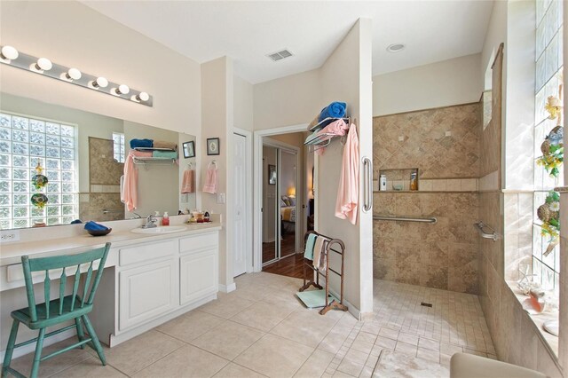 bathroom featuring hardwood / wood-style floors, oversized vanity, and tiled shower