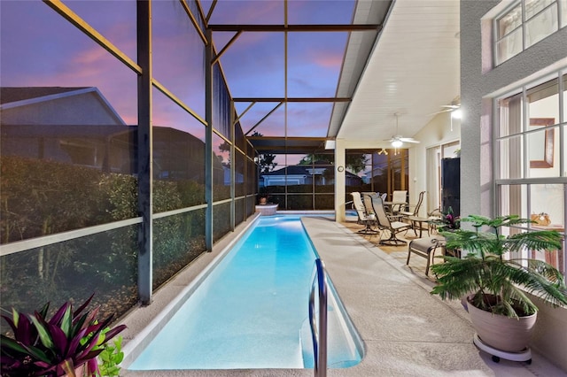 pool at dusk featuring a patio area, ceiling fan, and a lanai