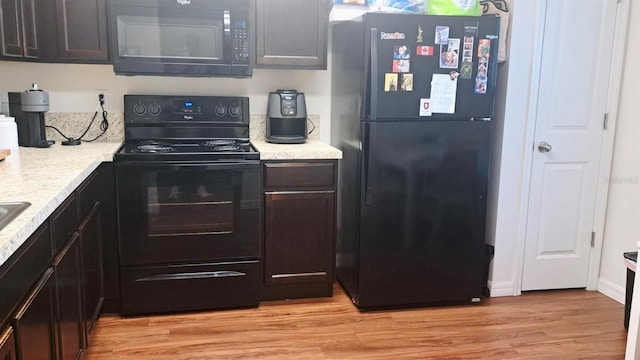 kitchen with light hardwood / wood-style floors, black appliances, and dark brown cabinetry