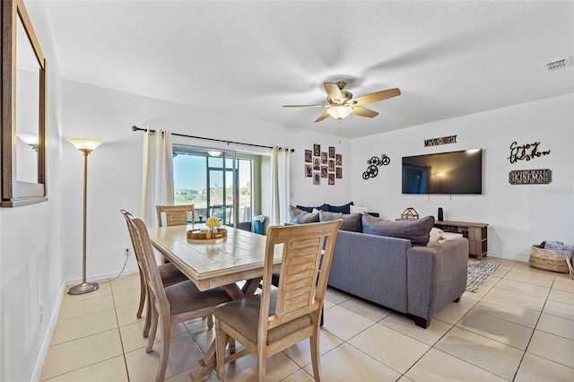 dining area with light tile floors, a textured ceiling, and ceiling fan