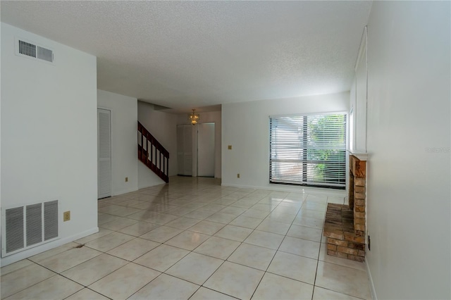 unfurnished living room with light tile patterned flooring and a textured ceiling