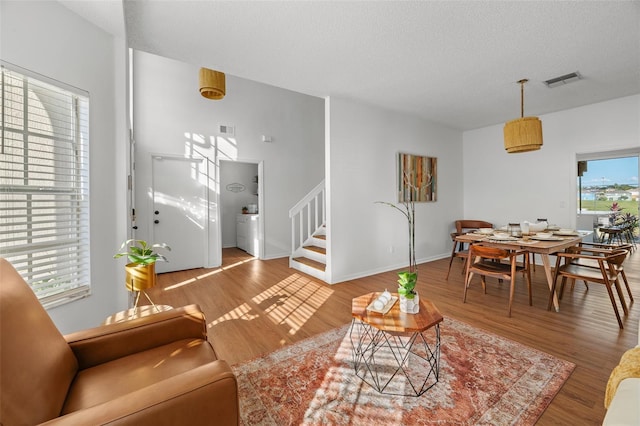 living room with light hardwood / wood-style flooring, washer / dryer, and a textured ceiling