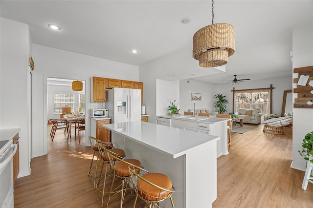 kitchen with a center island, ceiling fan with notable chandelier, light hardwood / wood-style flooring, stainless steel fridge, and a healthy amount of sunlight