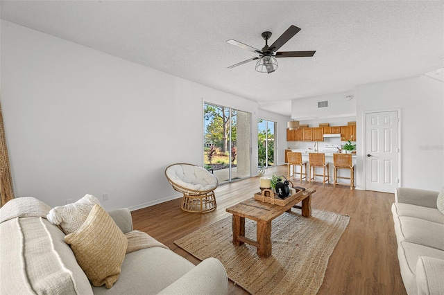 living room featuring a textured ceiling, ceiling fan, and light wood-type flooring