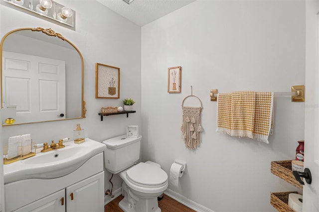 bathroom featuring a textured ceiling, toilet, vanity, and wood-type flooring