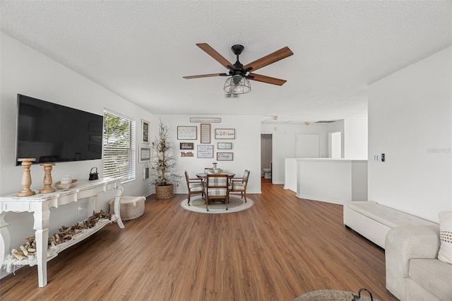 living room featuring hardwood / wood-style floors, ceiling fan, and a textured ceiling