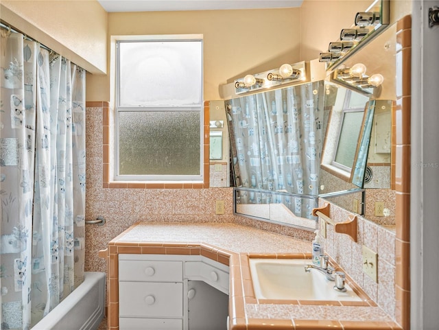 bathroom featuring tile walls, backsplash, vanity, and shower / bath combo