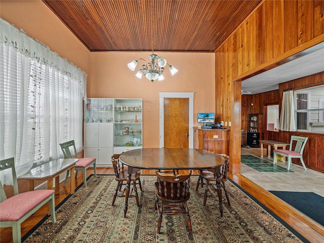 dining space with wooden walls, hardwood / wood-style floors, and a notable chandelier