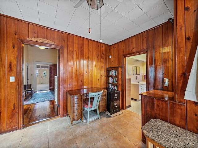 office with wooden walls, ceiling fan, and light tile floors