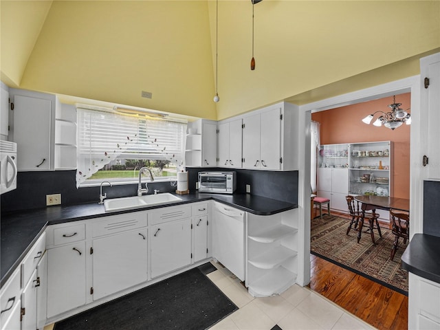 kitchen with a chandelier, white appliances, white cabinets, and light tile floors