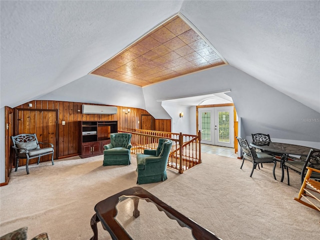 living room with lofted ceiling, wood walls, a textured ceiling, a wall mounted air conditioner, and light colored carpet