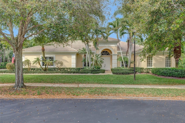 view of front of house with a front yard, a tile roof, and stucco siding