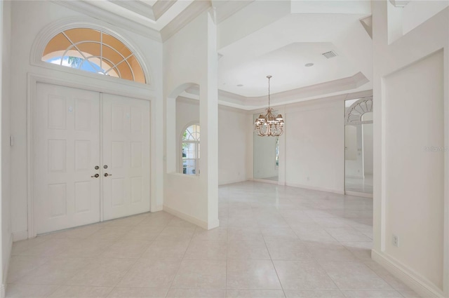 entryway featuring a tray ceiling, crown molding, baseboards, and an inviting chandelier