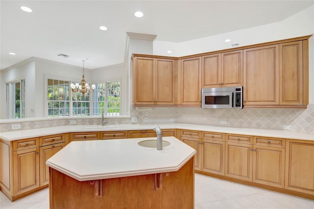 kitchen with light countertops, a kitchen island with sink, and stainless steel microwave