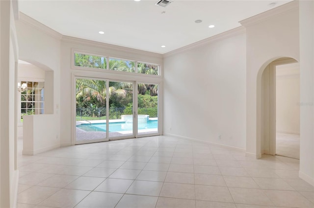 empty room with arched walkways, ornamental molding, light tile patterned floors, and baseboards