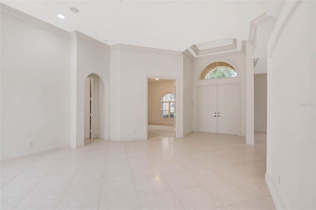 foyer entrance with baseboards, arched walkways, crown molding, and light tile patterned flooring