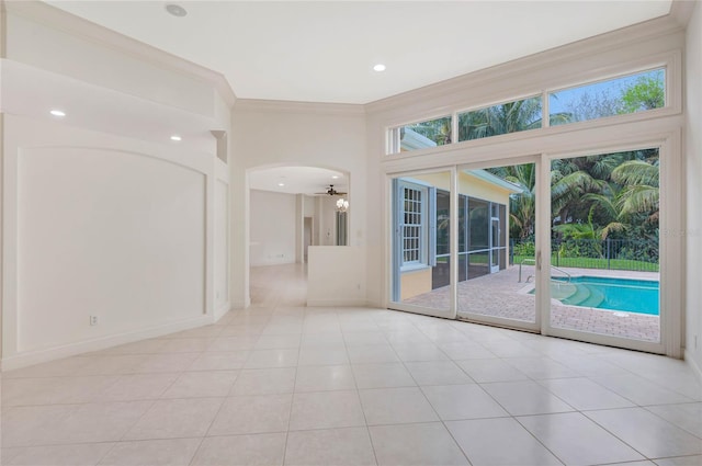 spare room with light tile patterned floors, baseboards, arched walkways, crown molding, and recessed lighting