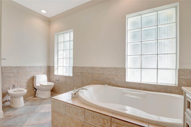 full bathroom featuring a garden tub, toilet, vanity, ornamental molding, and a bidet