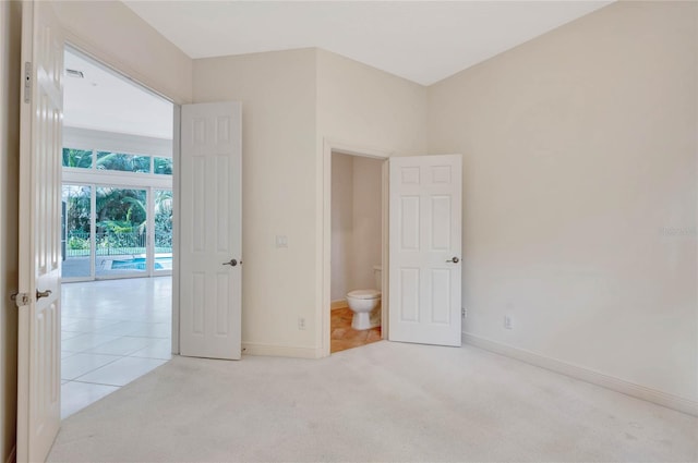 unfurnished bedroom featuring light carpet, light tile patterned floors, and baseboards