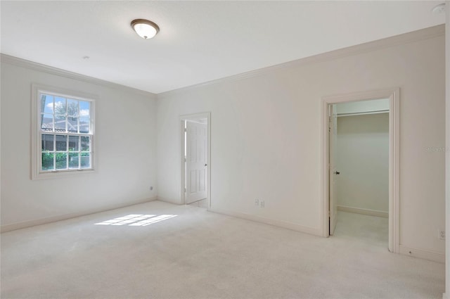 unfurnished bedroom with ornamental molding, a walk in closet, light colored carpet, and baseboards