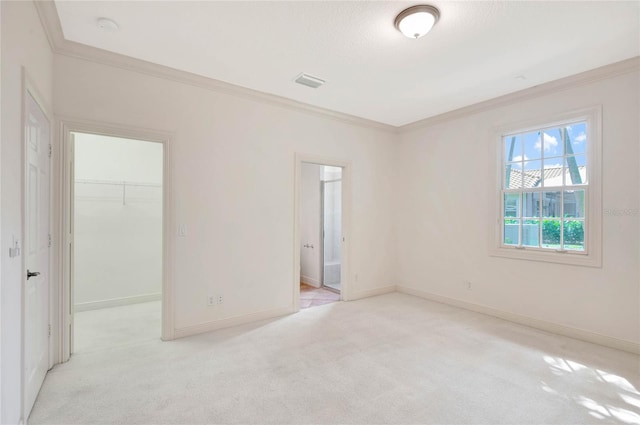 unfurnished room with ornamental molding, light colored carpet, visible vents, and baseboards