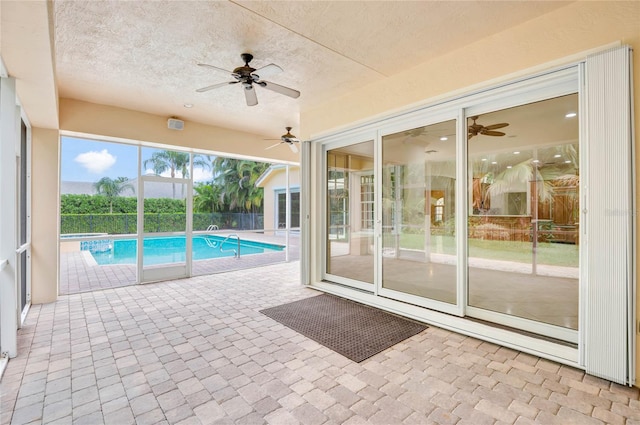 view of swimming pool with a patio area, a pool with connected hot tub, fence, and a ceiling fan