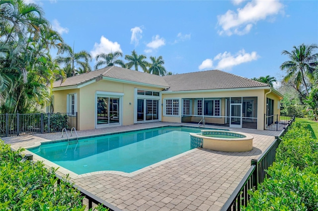 view of swimming pool with a sunroom, a pool with connected hot tub, fence, and a patio