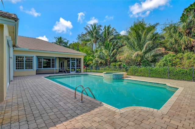 view of pool with a pool with connected hot tub, fence, and a patio