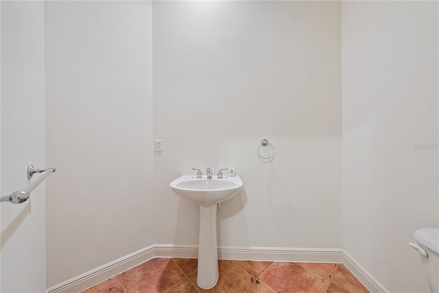 half bath featuring baseboards, tile patterned floors, and toilet